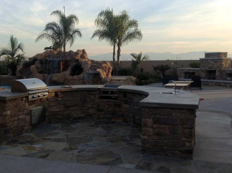 A patio with a grill and palm trees in the background
