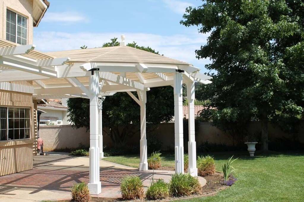 A white gazebo in the backyard of a house
