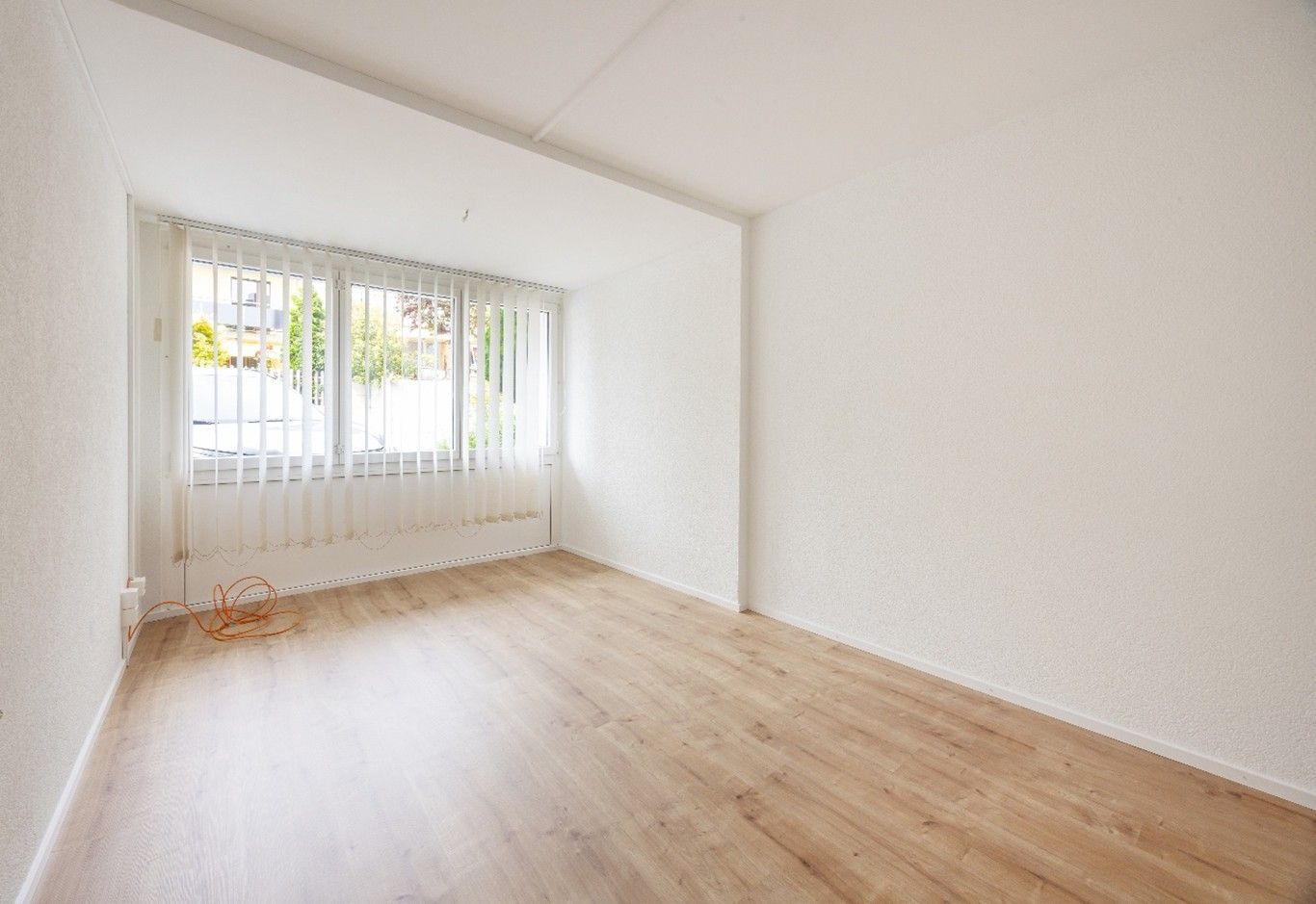 Ein leeres Wohnzimmer mit Hartholzböden und weißen Wänden.