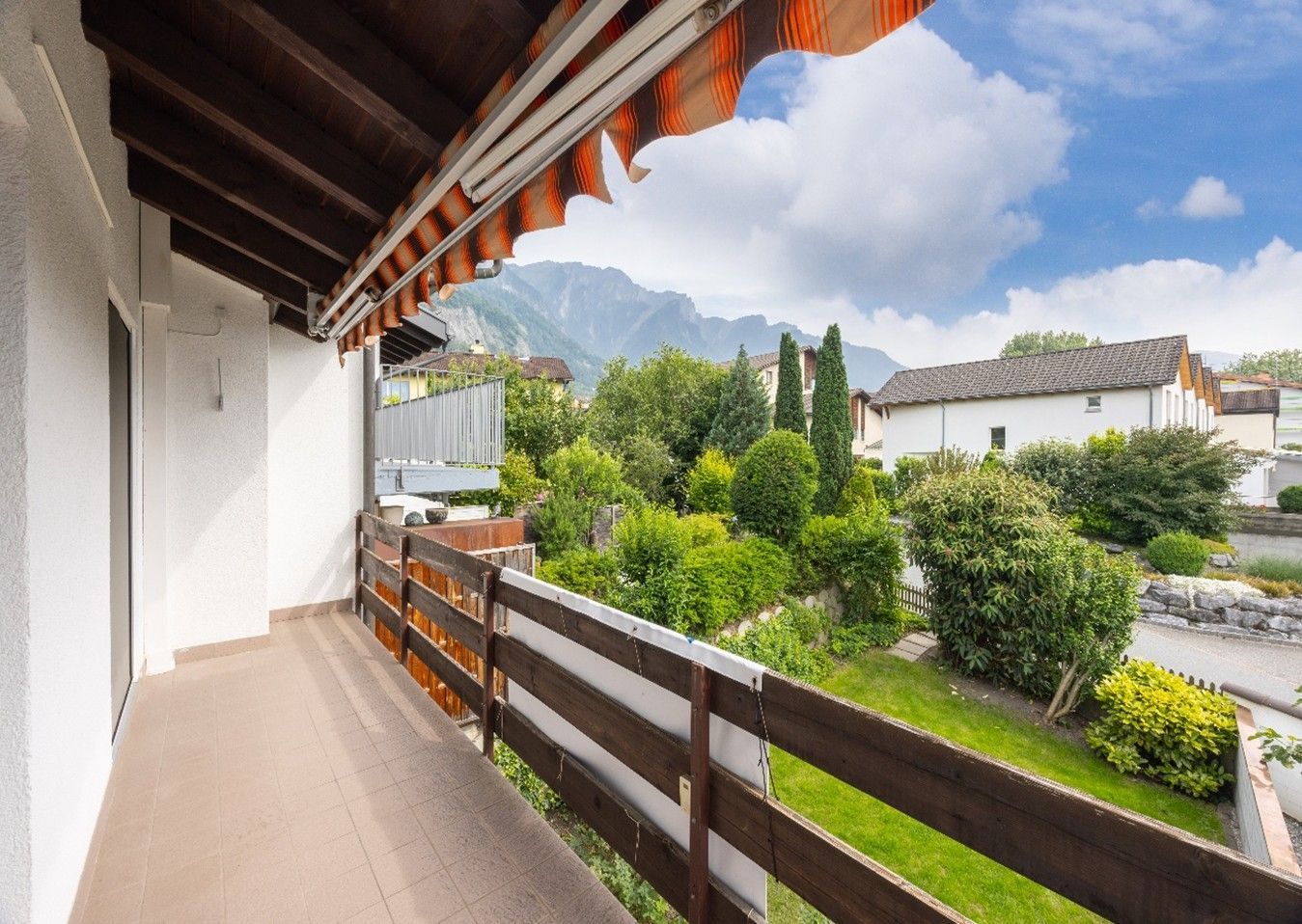 Ein Balkon mit Holzgeländer und Bergen im Hintergrund