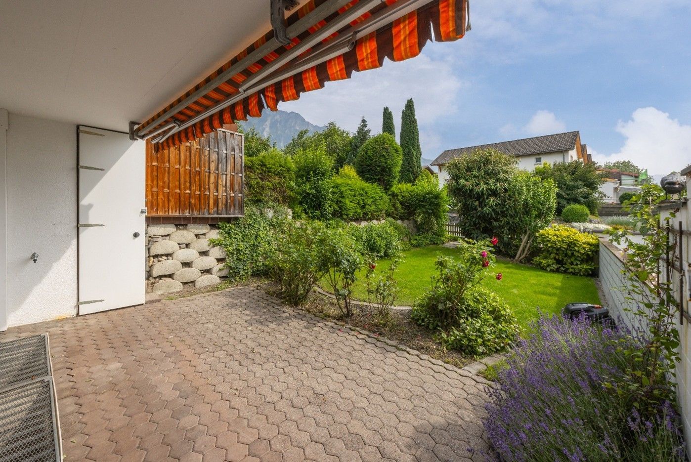 Es gibt eine überdachte Terrasse und im Hintergrund einen Garten.