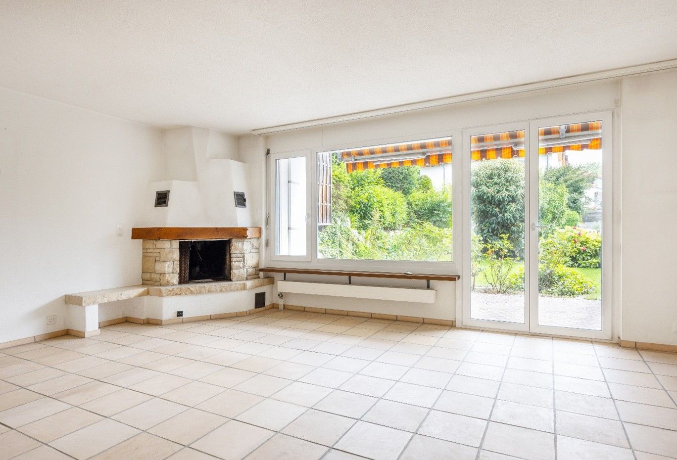 Ein leeres Wohnzimmer mit Kamin und vielen Fenstern.