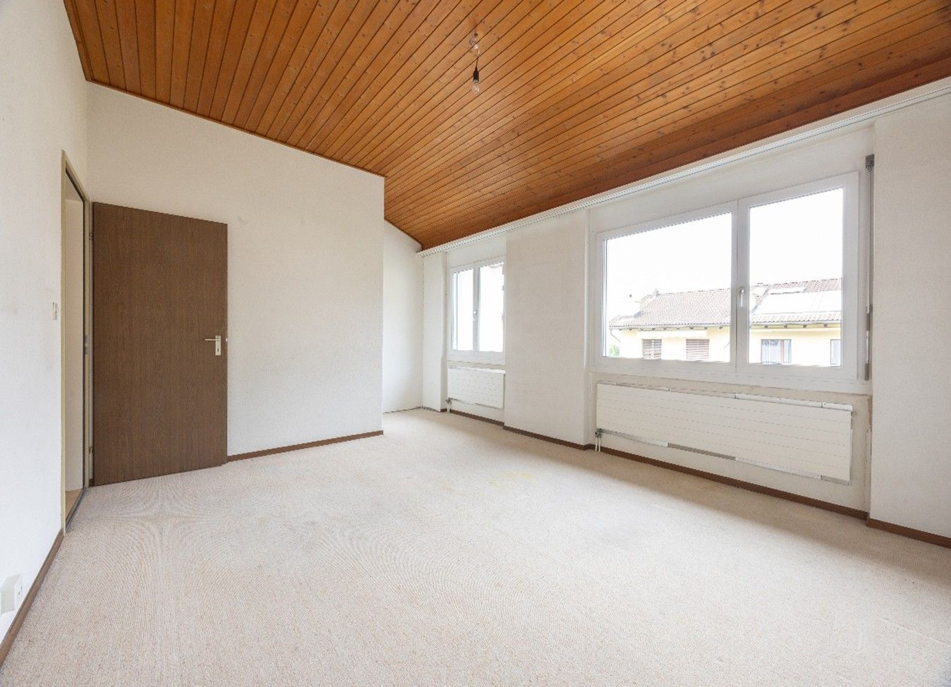 Ein leerer Raum mit einer Holzdecke und zwei Fenstern.