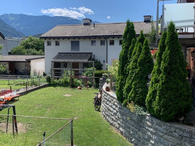 Grüner, überschaubarer Garten mit einem Haus im Hintergrund