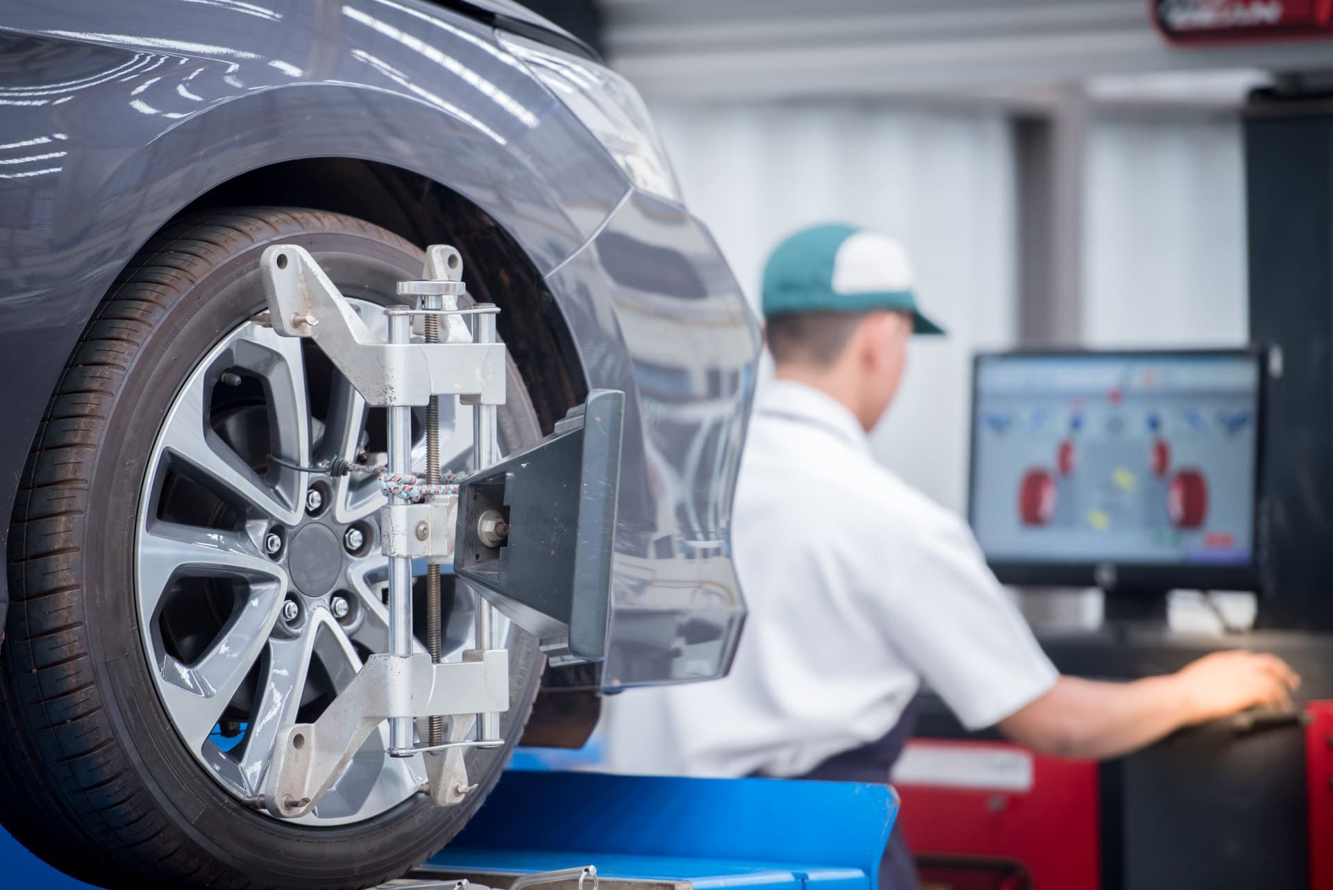 Car mechanic installing sensor during suspension adjustment. Wheel alignment work at repair service station
