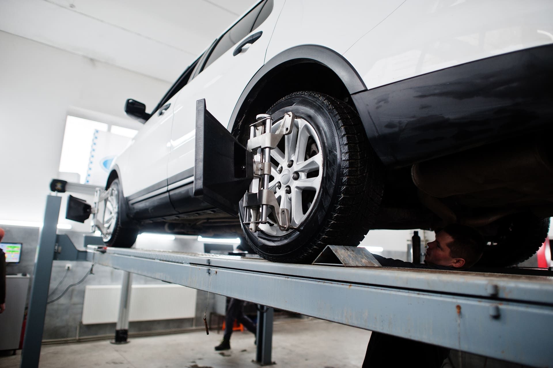 American SUV car on stand for wheels alignment camber check in workshop of service station