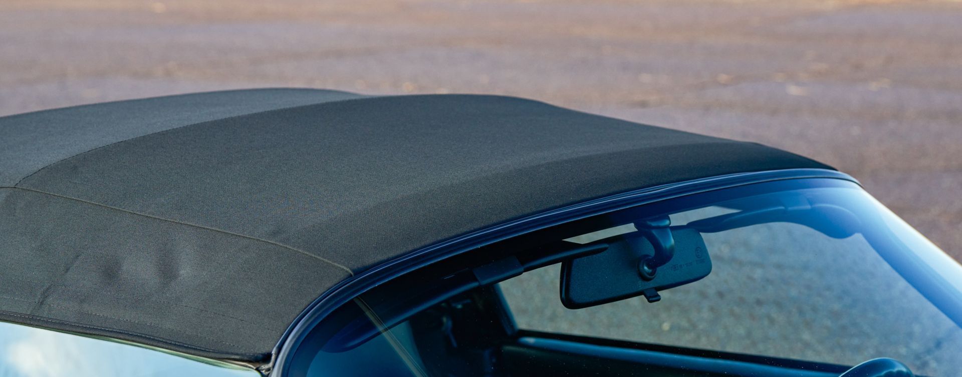 A close up of a car with a black top and a windshield.