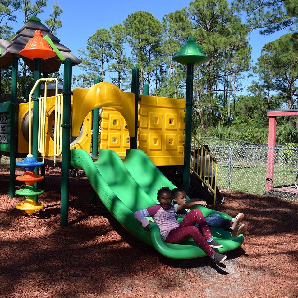 A classroom with tables and chairs and a blue rug.