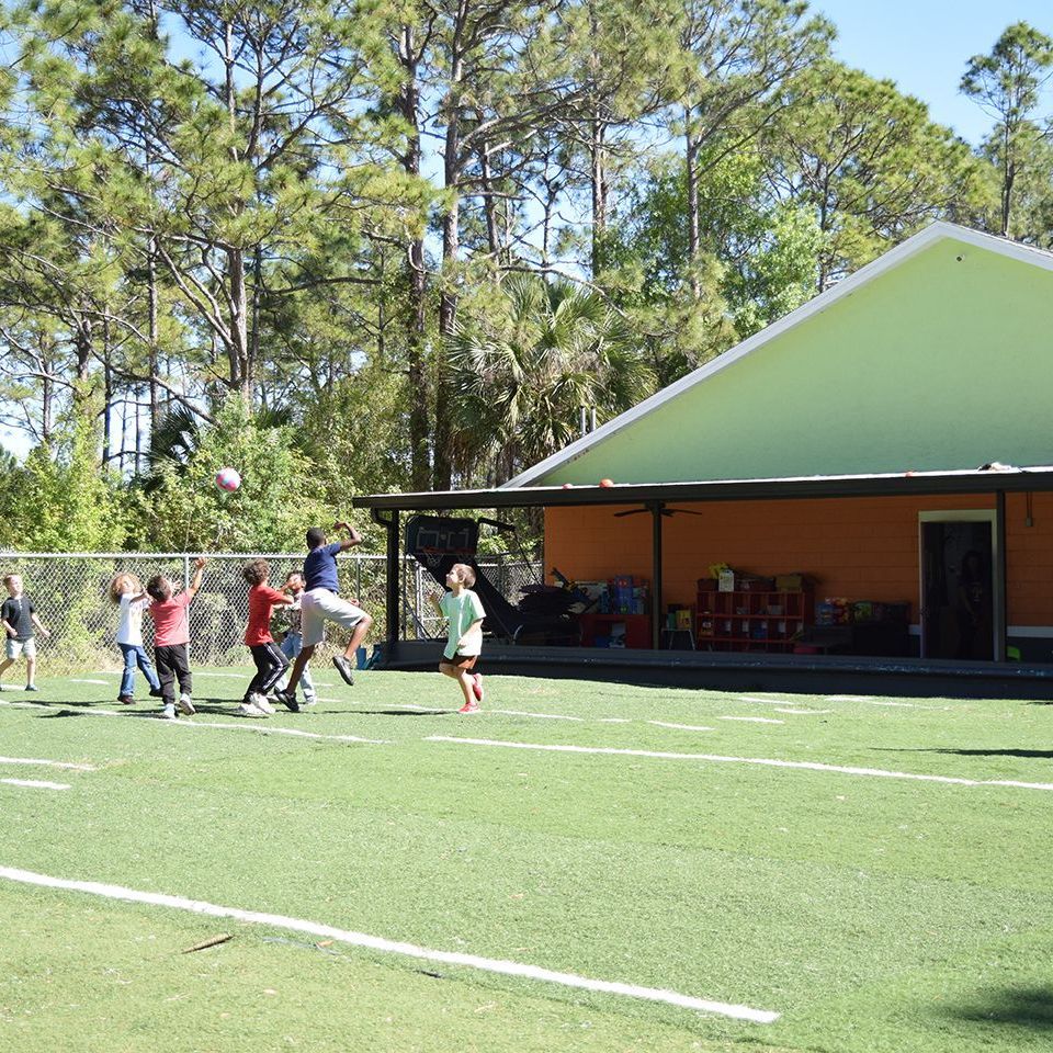 A classroom with tables and chairs and a rug that says little one.
