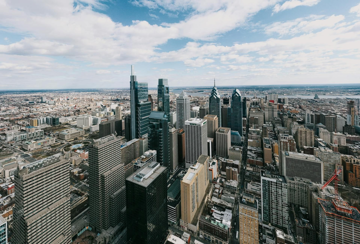 Aerial view of Philadelphia skyline with tall skyscrapers under a cloudy sky.