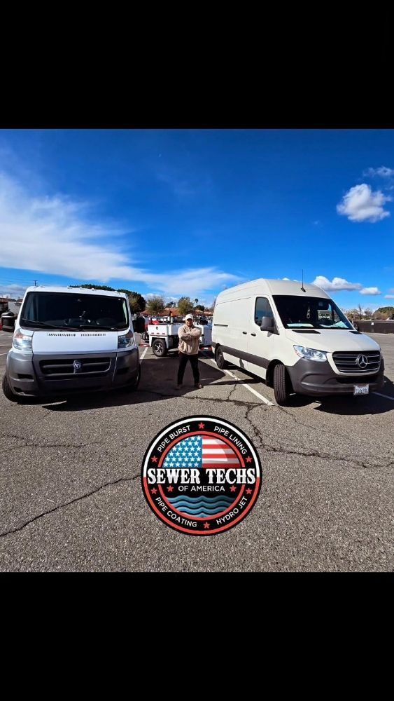 Two white vans parked; logo 