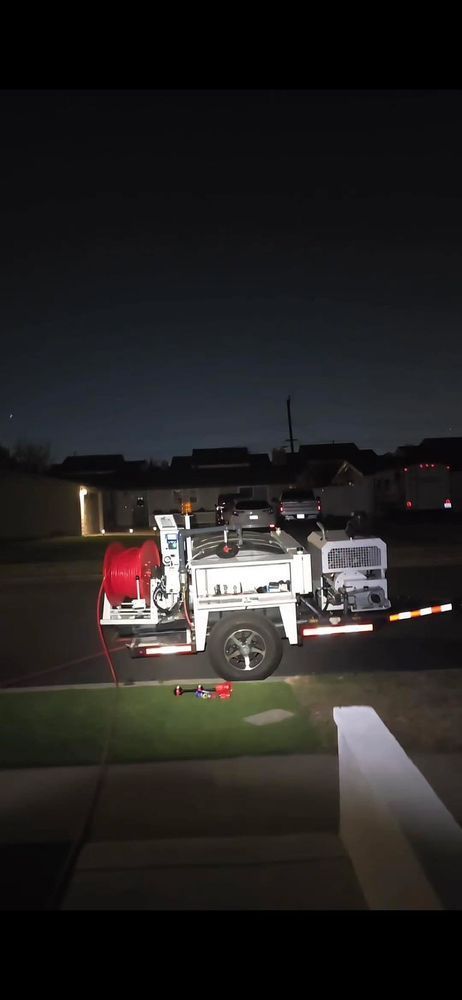 A white work truck parked at night on a grassy area in front of houses.
