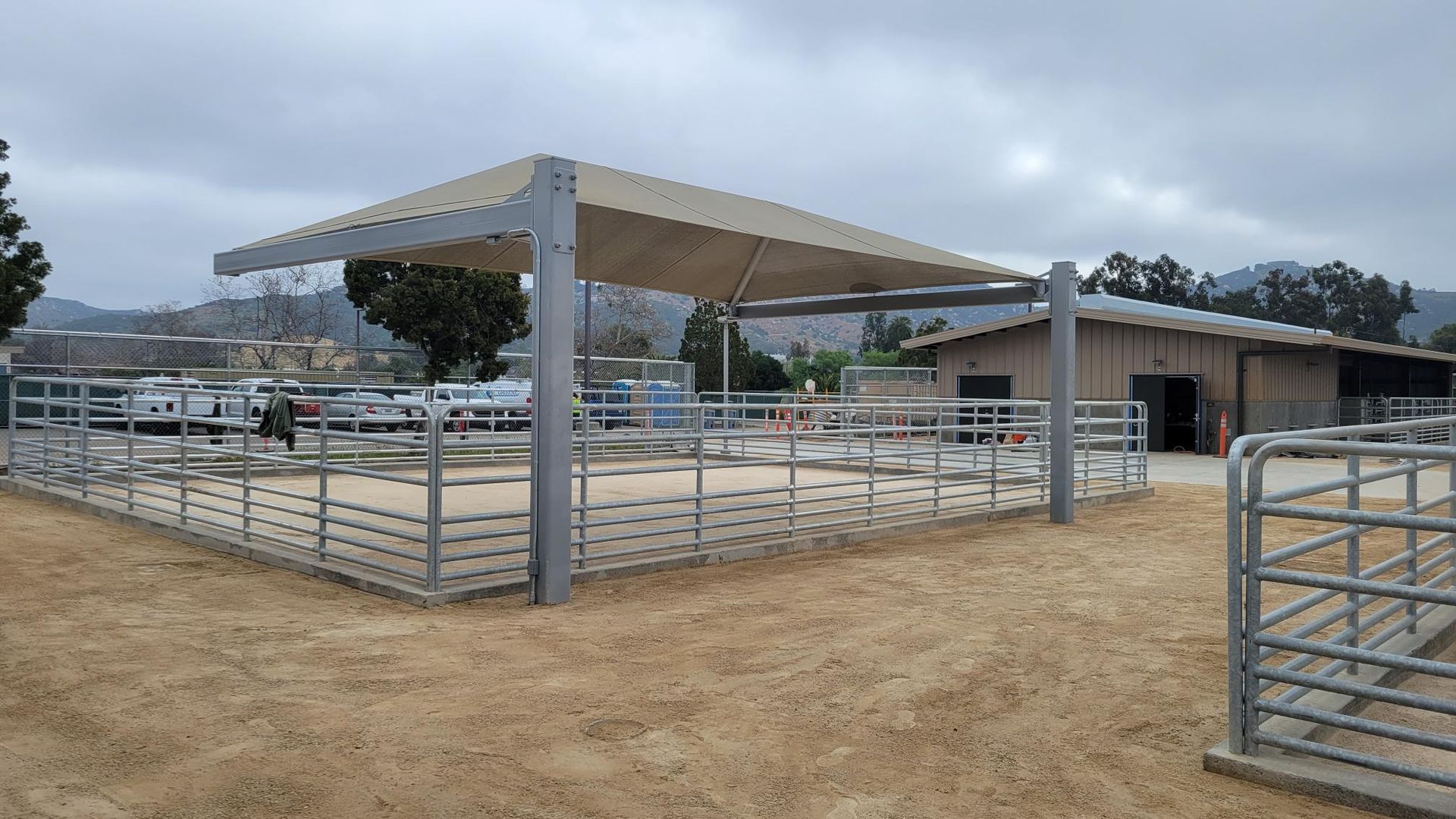 A fenced in area with a canopy over it and a building in the background.