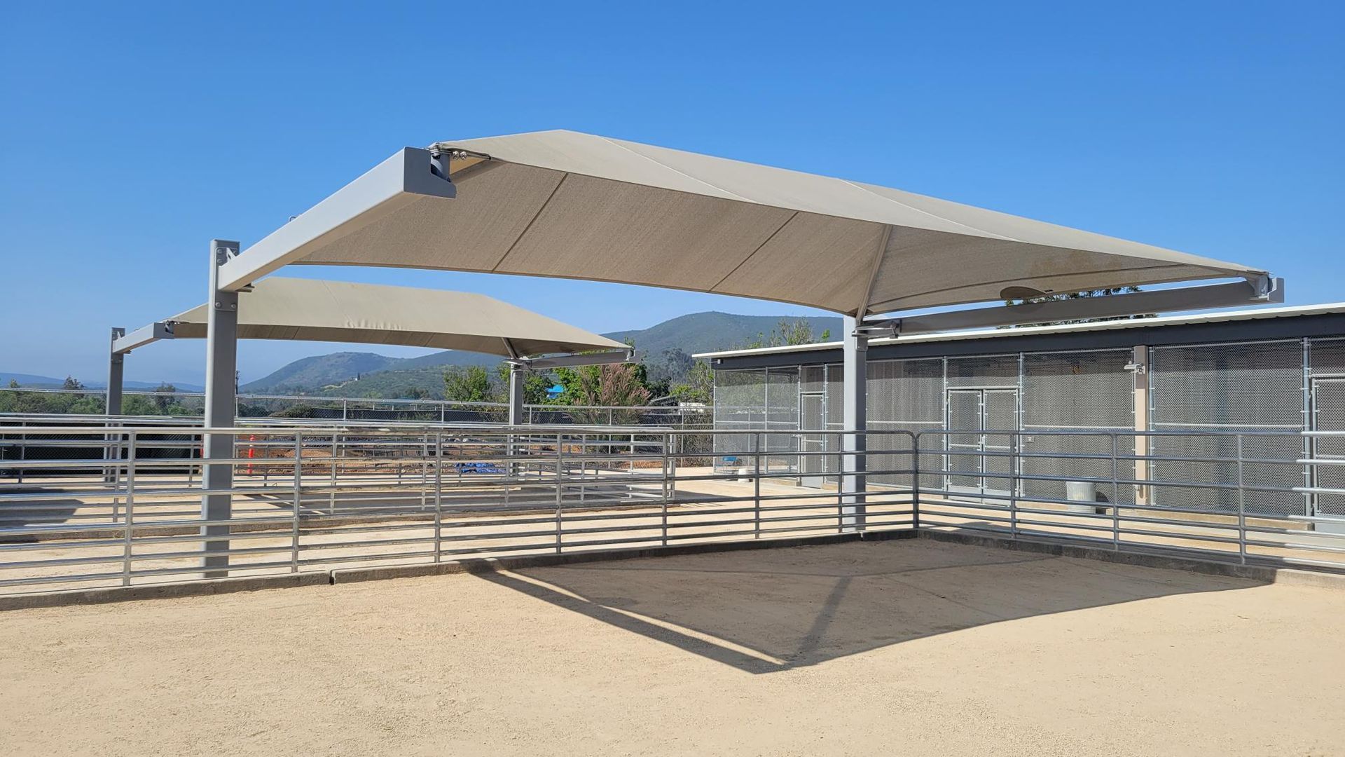 A large white umbrella is sitting on top of a dirt field.
