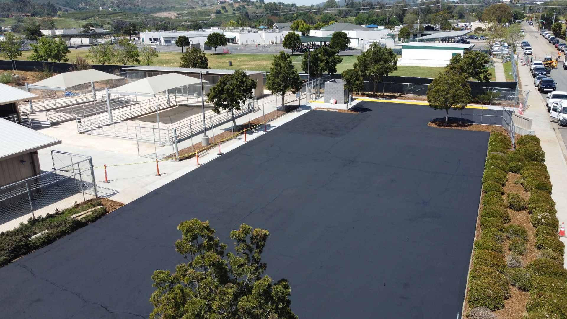 An aerial view of a large asphalt parking lot in front of a building.