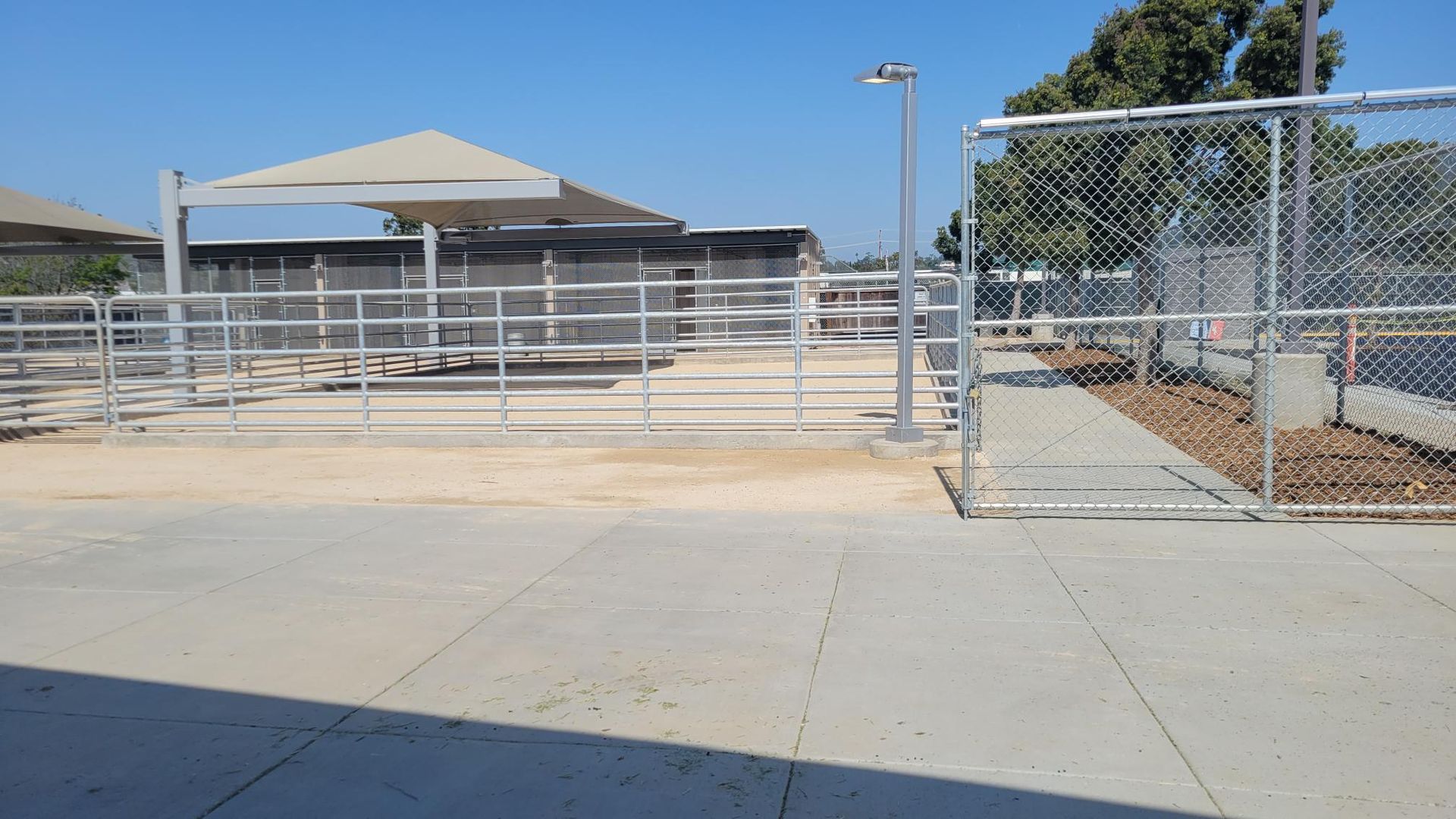 A chain link fence surrounds a concrete walkway leading to a building.