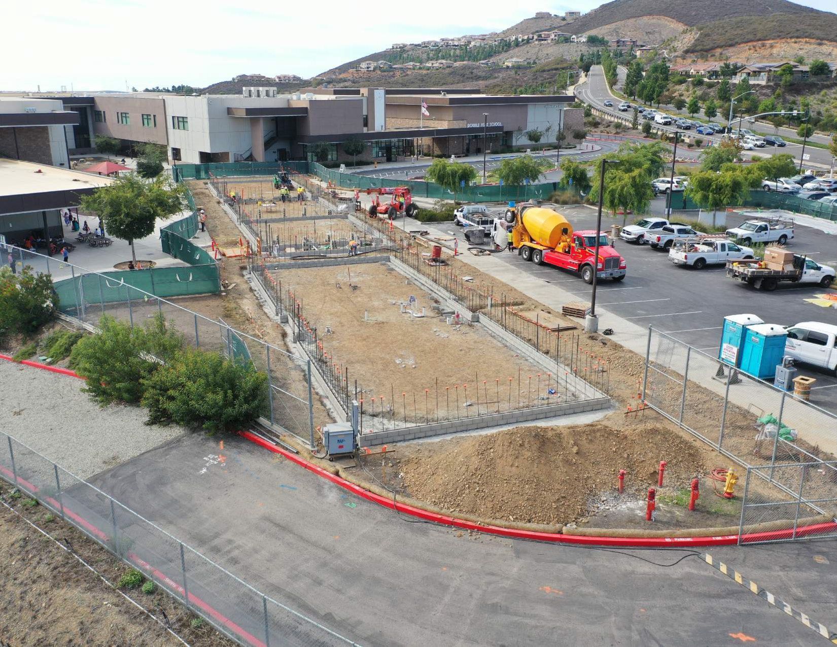 An aerial view of a construction site with a red truck driving down the road.