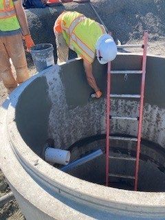 A man is working on a concrete well with a ladder.