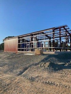 A large metal building is being built in a dirt field.