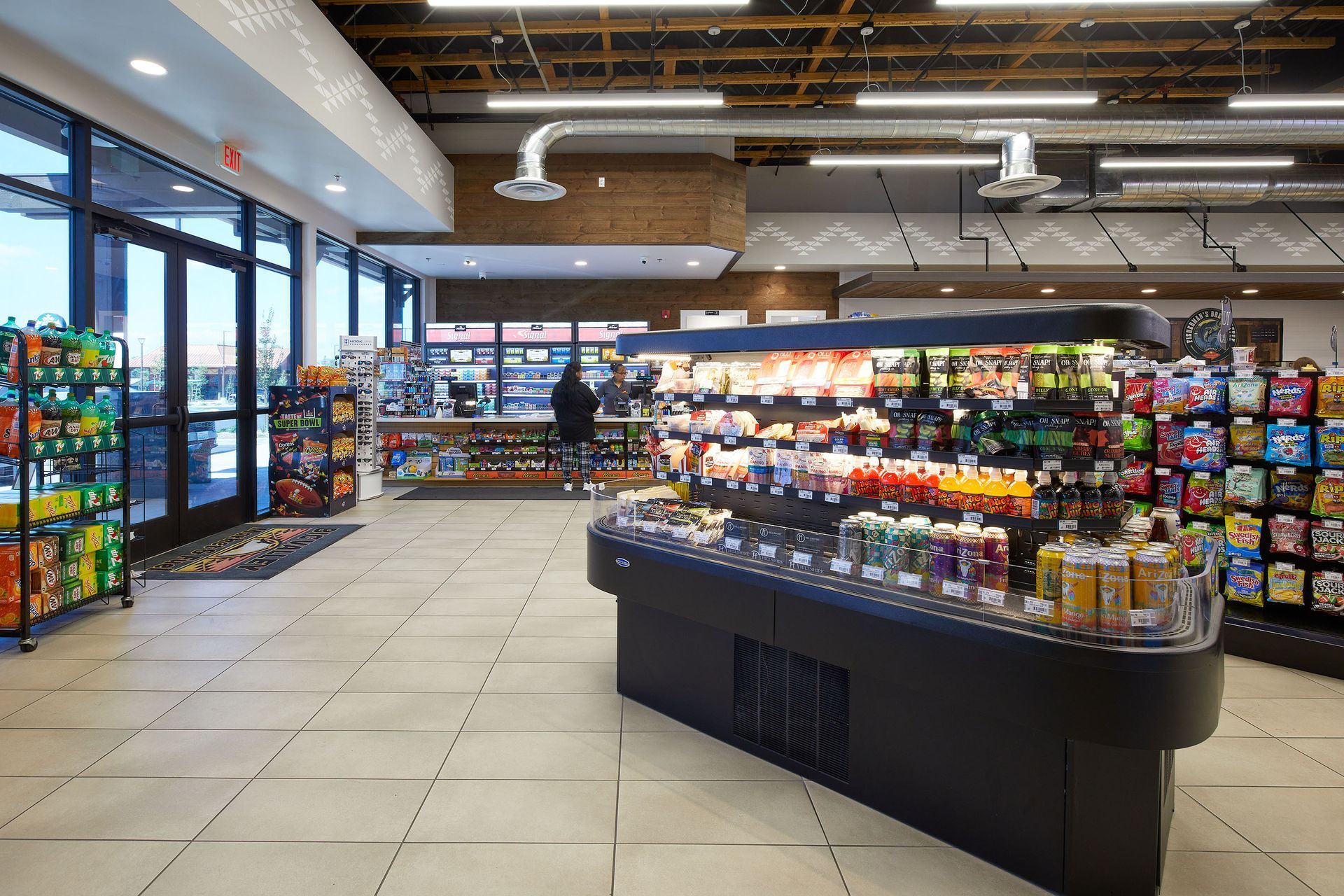 Convenience store interior with aisles of snacks, drinks, and a central refrigerated display