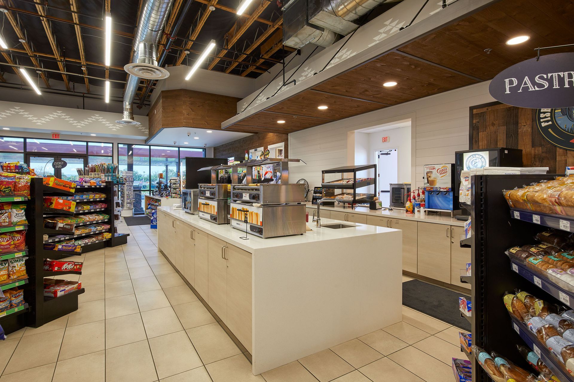Bright bakery/café interior with display shelves, white counter, and pastry cases under warm lighting