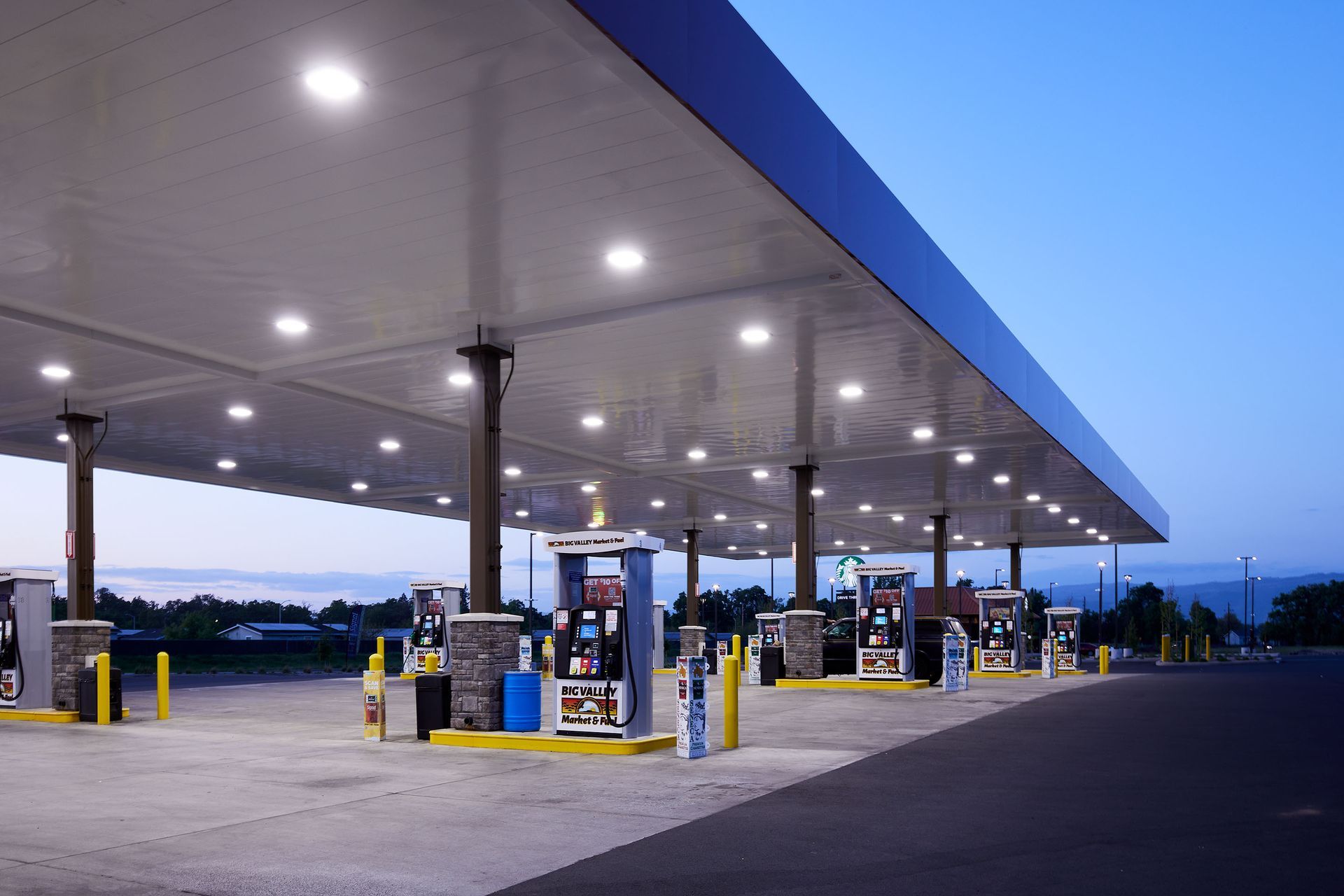 Empty gas station at dusk with lit pumps under a wide canopy