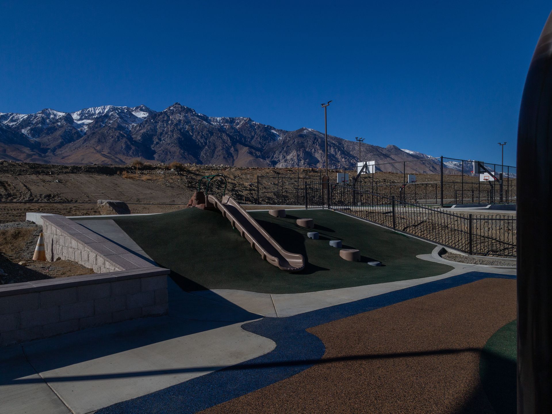 Playground with slide and mountain backdrop under a clear blue sky.