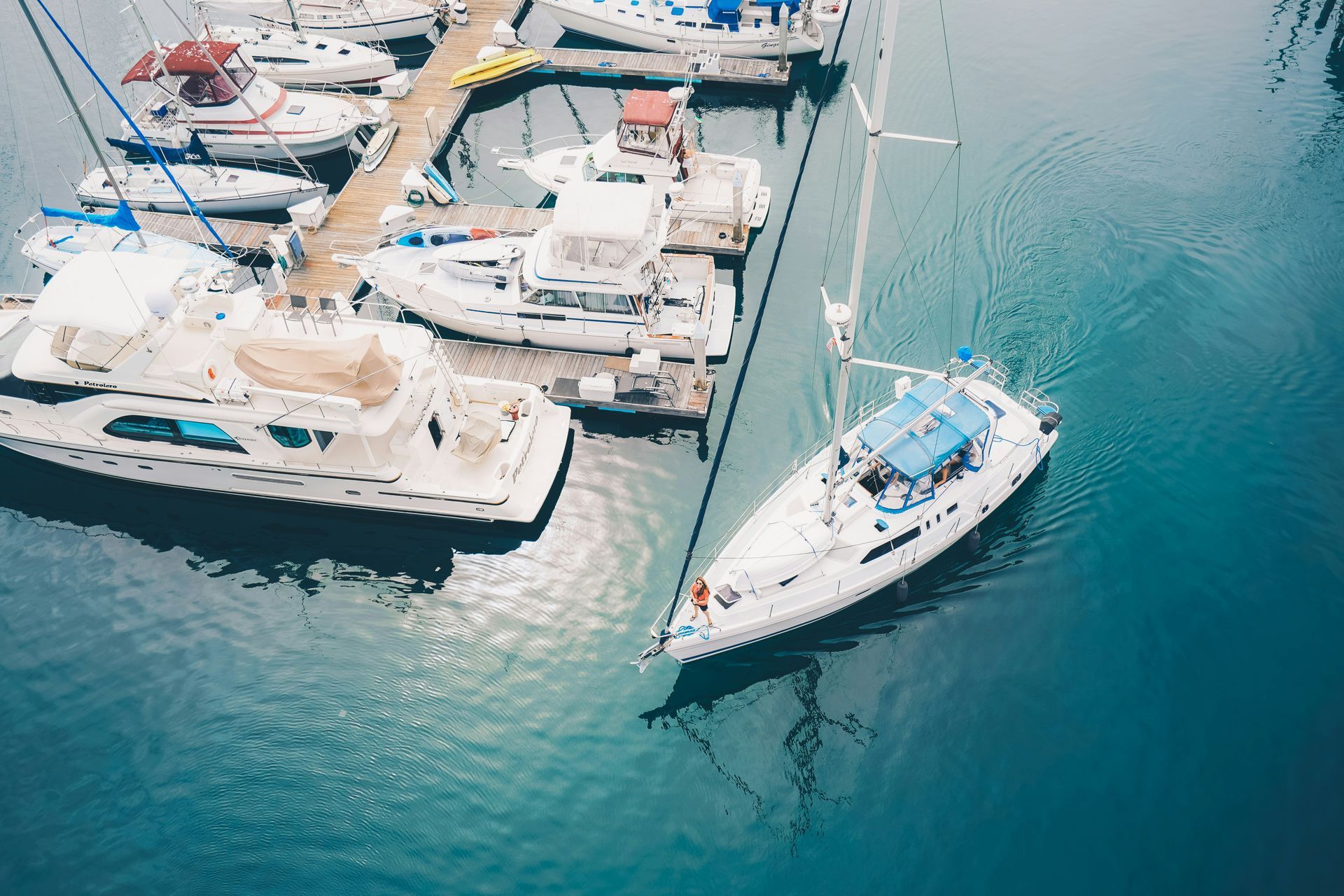 Boats docked at a marina; white sailboats and motorboats in blue water.