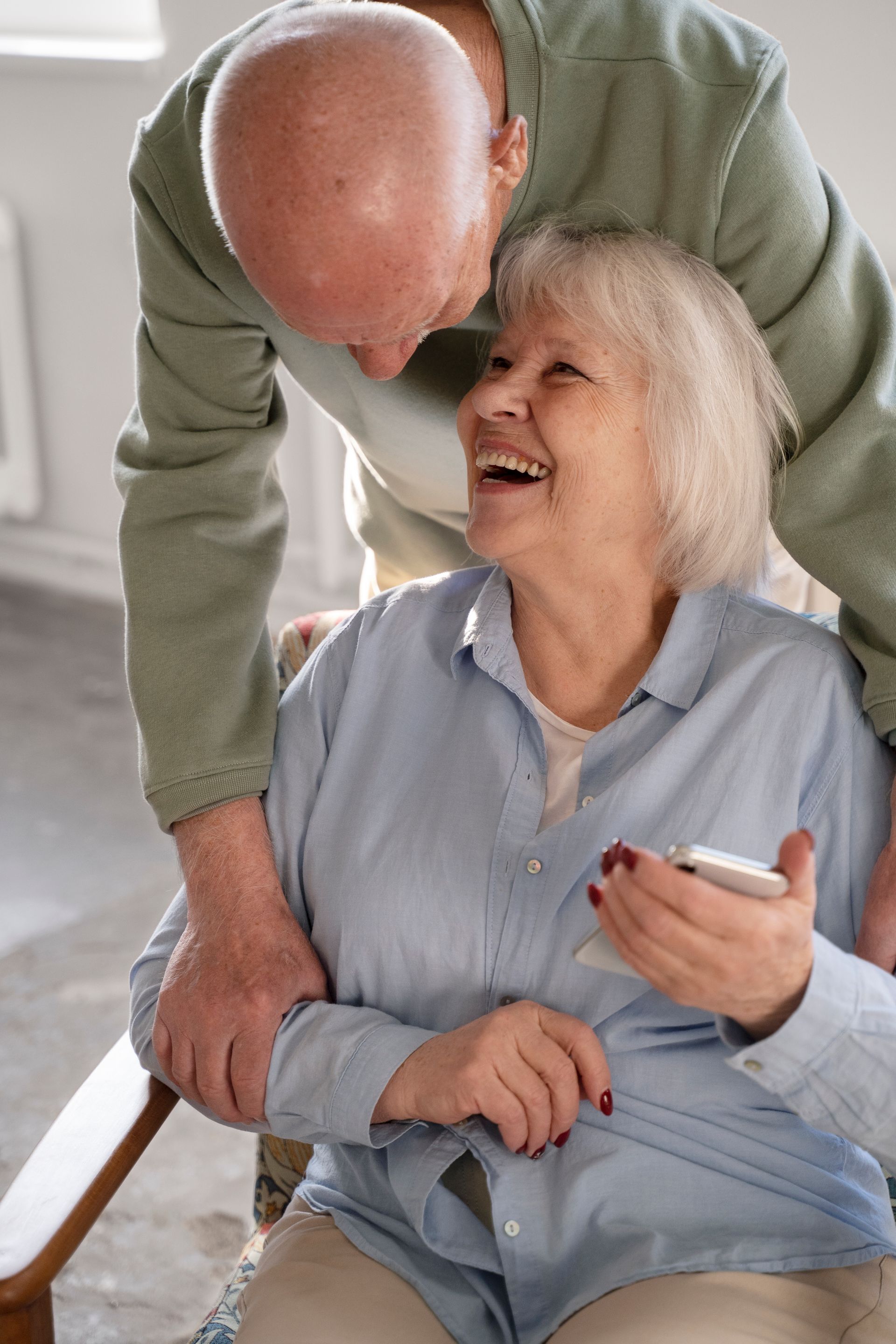Smiling woman being embraced by a man indoors. They appear happy.