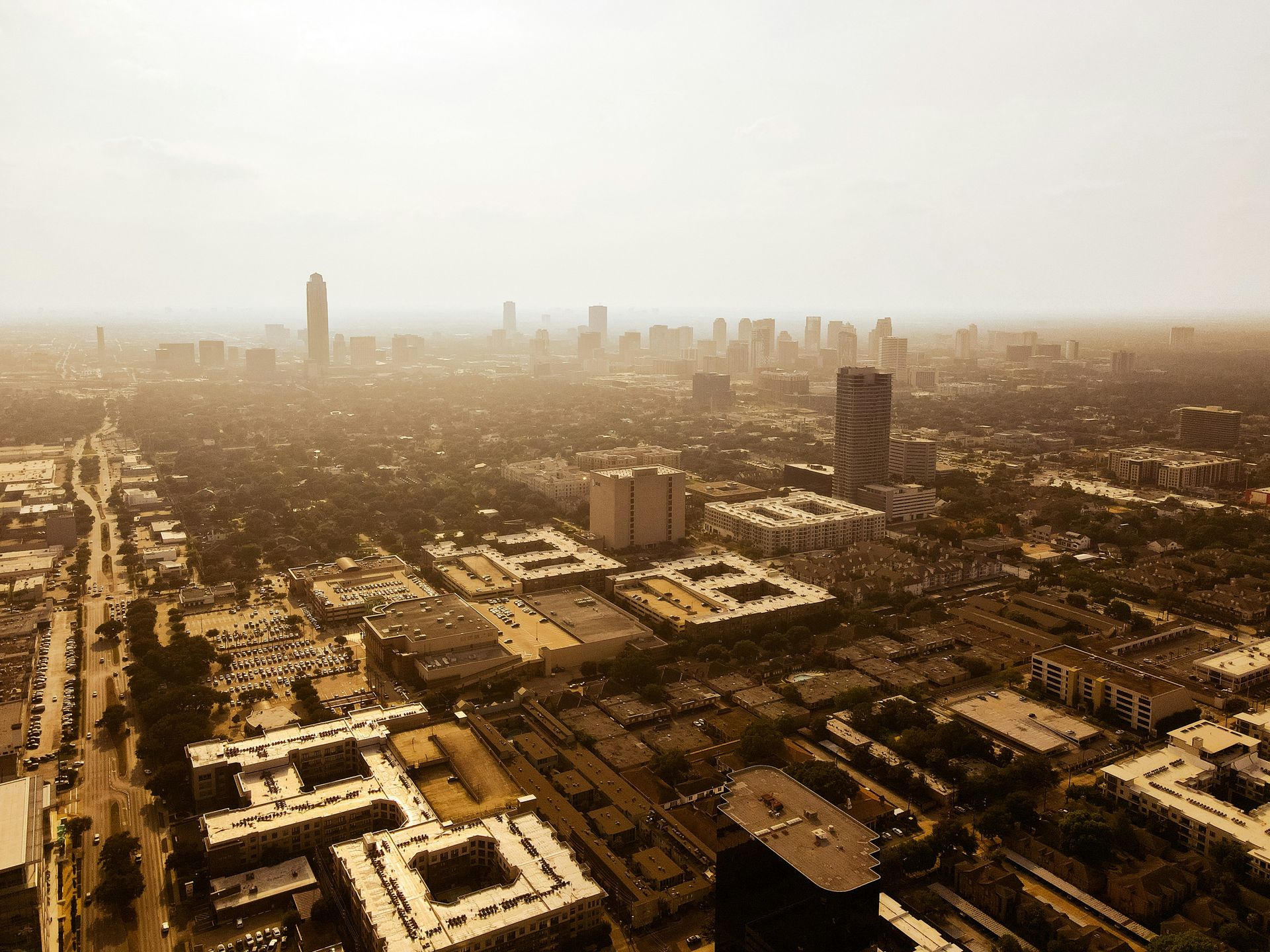 Aerial view of a city skyline on a hazy day. Buildings of various heights are visible.