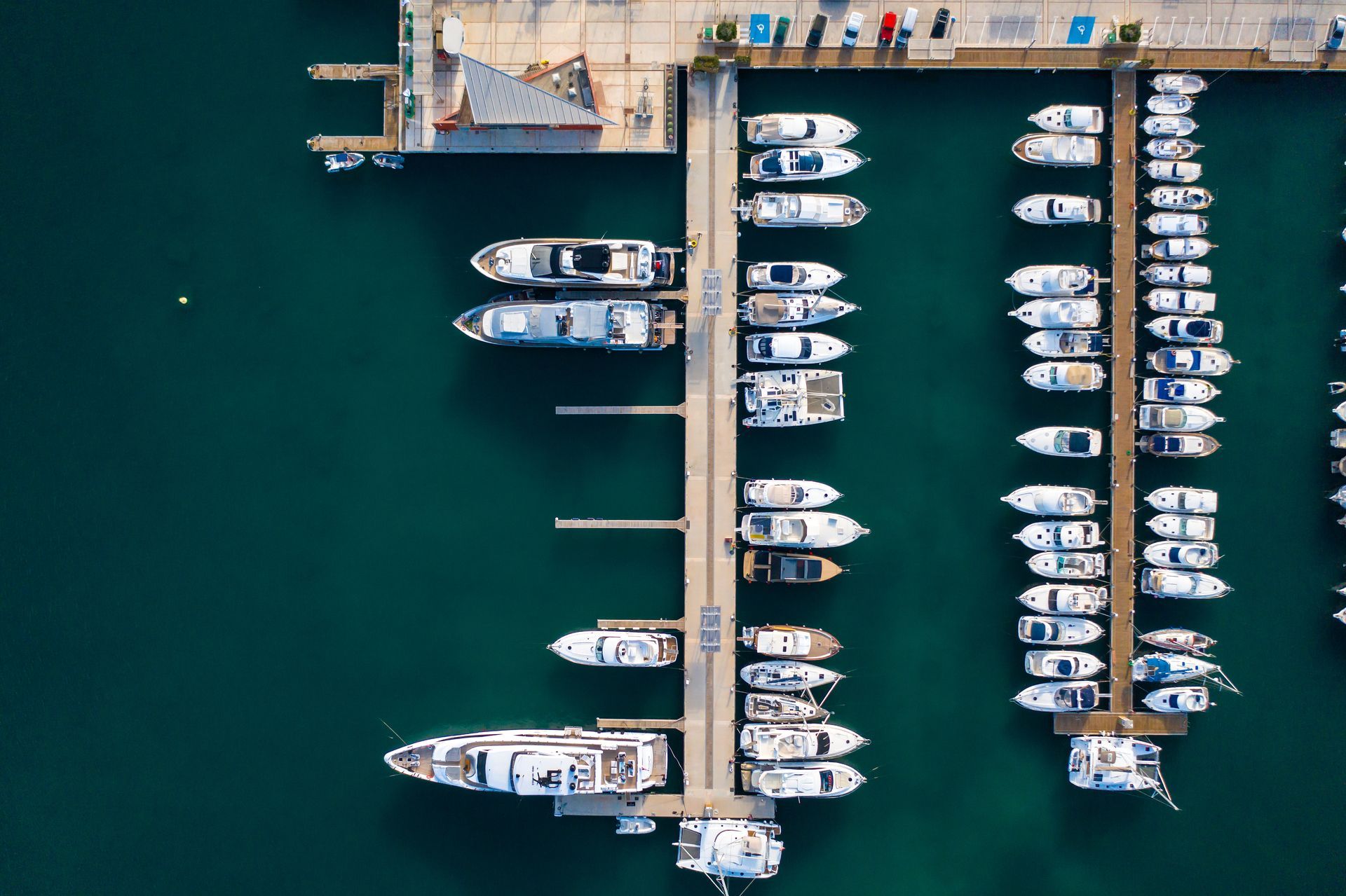 Aerial view of a marina with many docked white boats and green water.