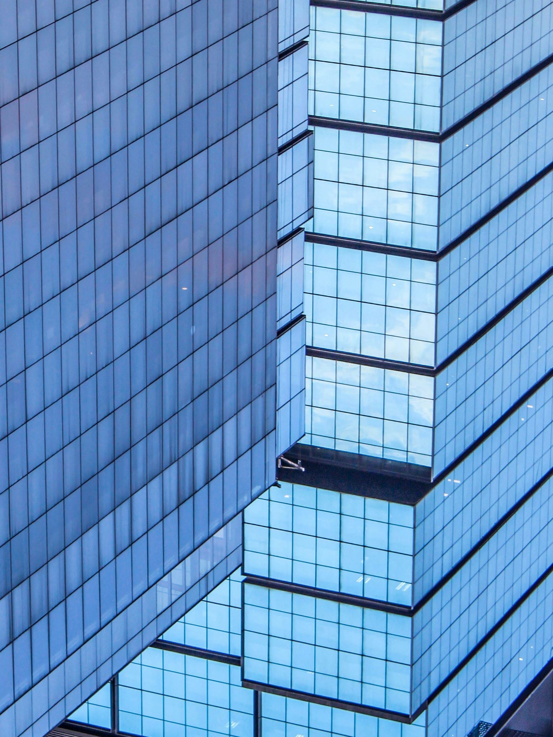 Two modern glass skyscrapers with a blue hue, reflecting the sky.