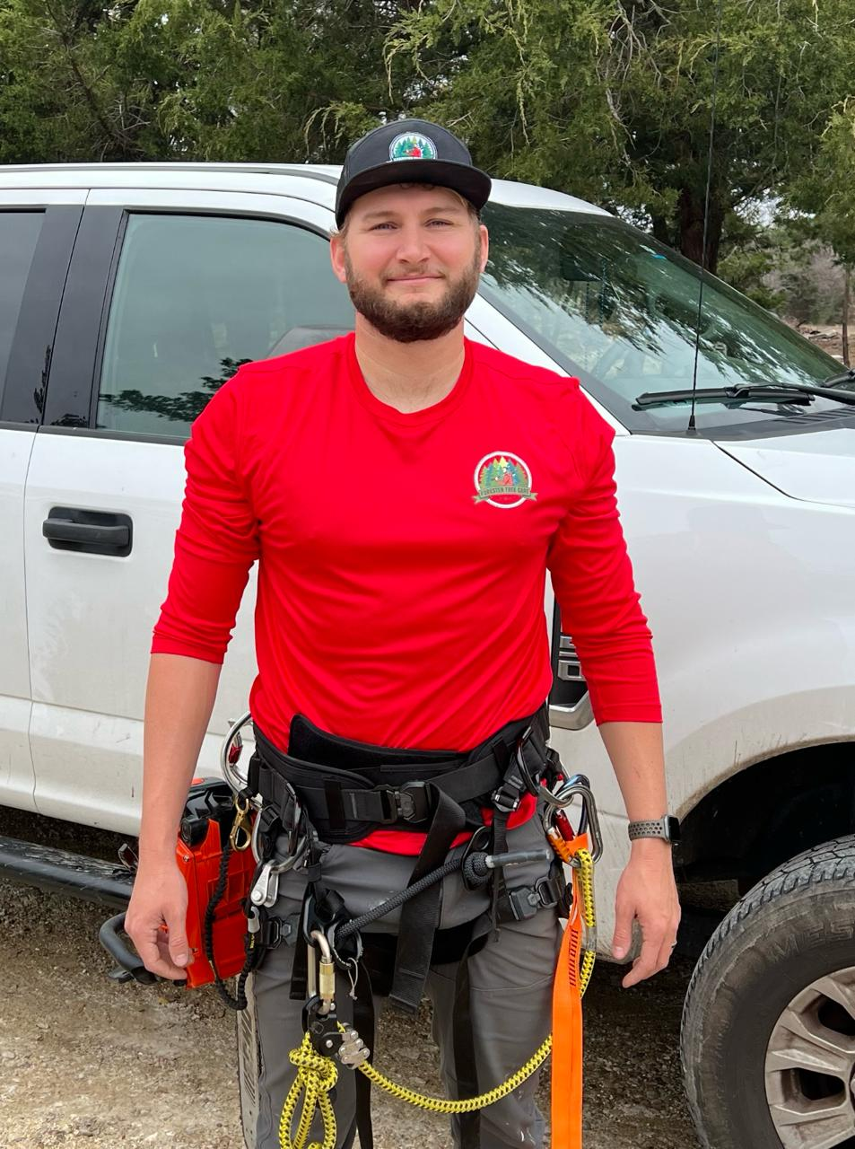 A man in a red shirt is standing in front of a white truck.