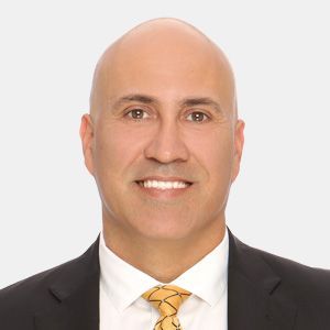 A bald man in a suit and tie is smiling for the camera.