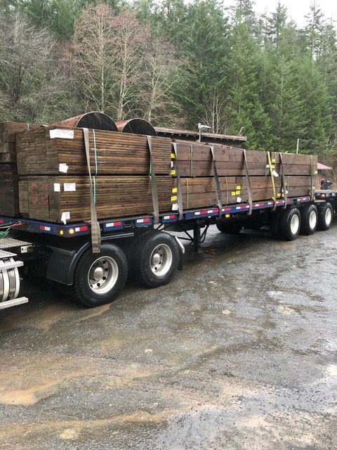 A semi truck is carrying a load of wood on a trailer.