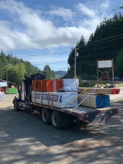 A truck is carrying a load of lumber on a trailer.