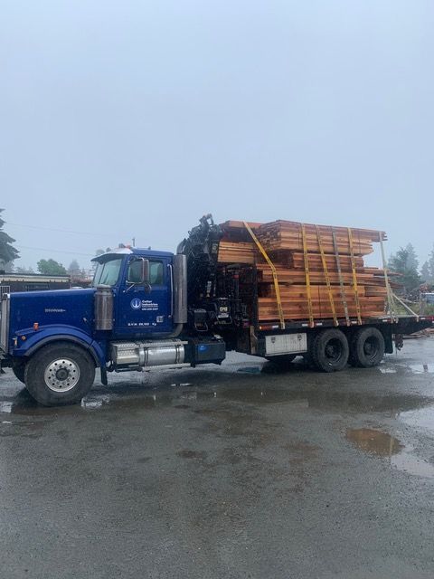 A blue truck is carrying a stack of wood.