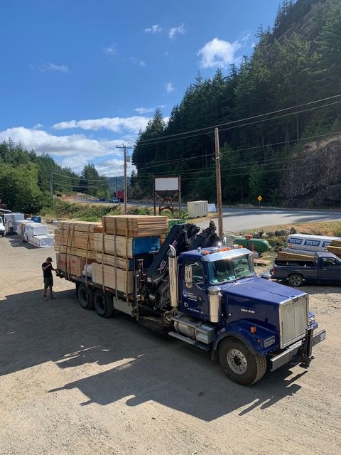 A blue semi truck is loaded with wooden crates in a parking lot.