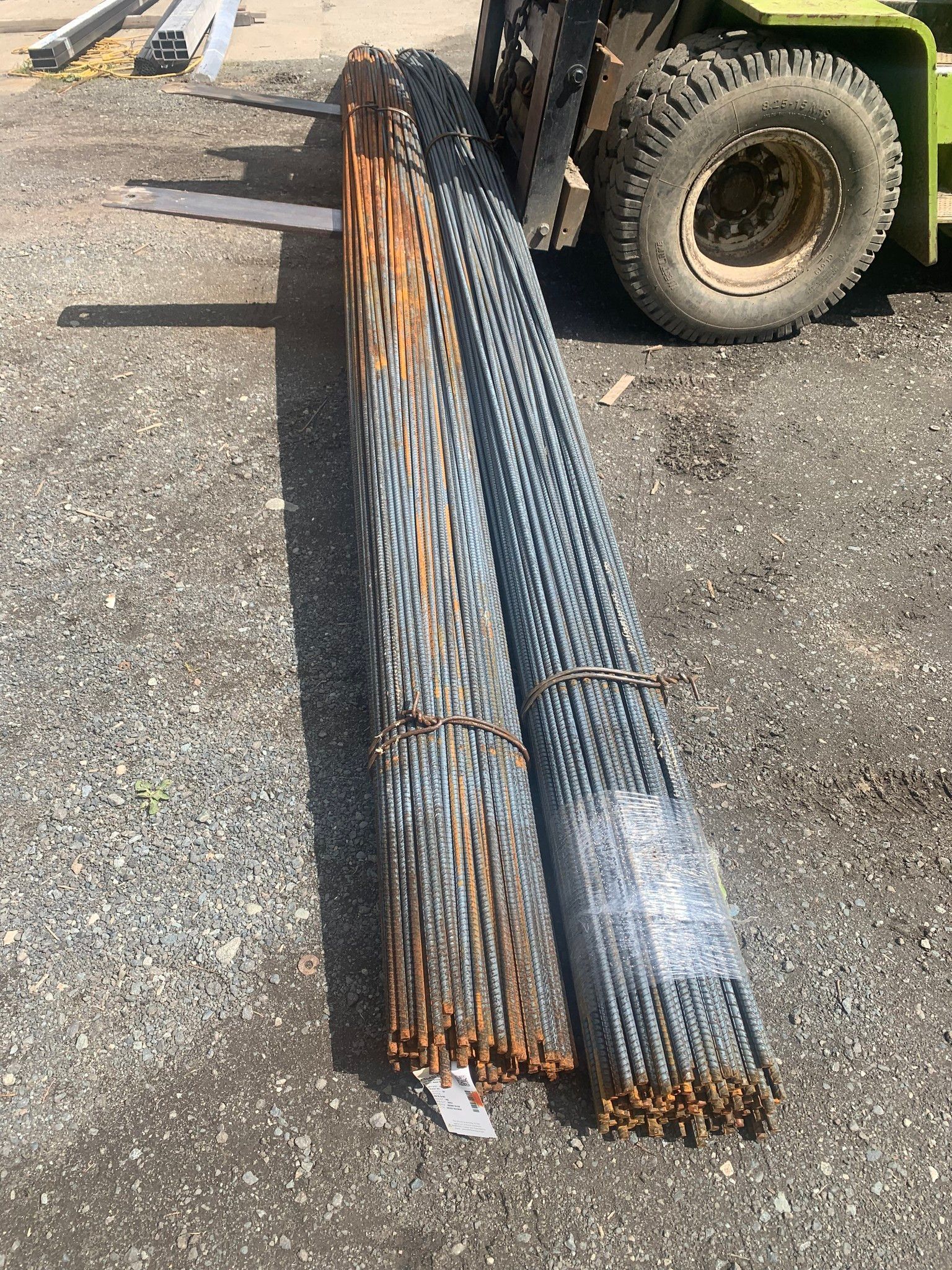 A forklift is carrying a bunch of metal bars on the ground.