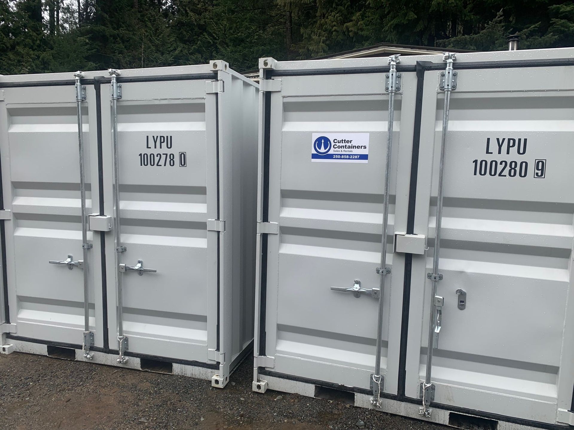 A row of white shipping containers are lined up in a parking lot.