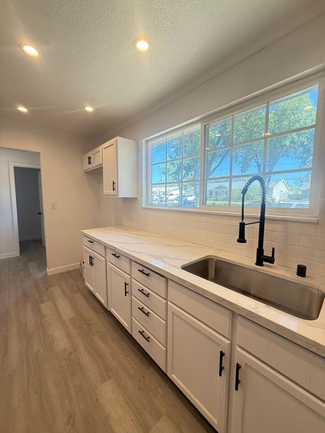 White kitchen with a sink, cabinets, countertop, window, and black faucet.
