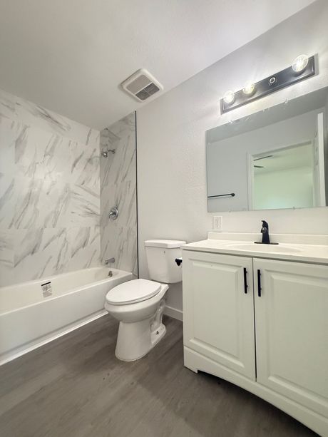 Modern white bathroom with marble-look shower wall, white vanity, gray floor, and a mirror.