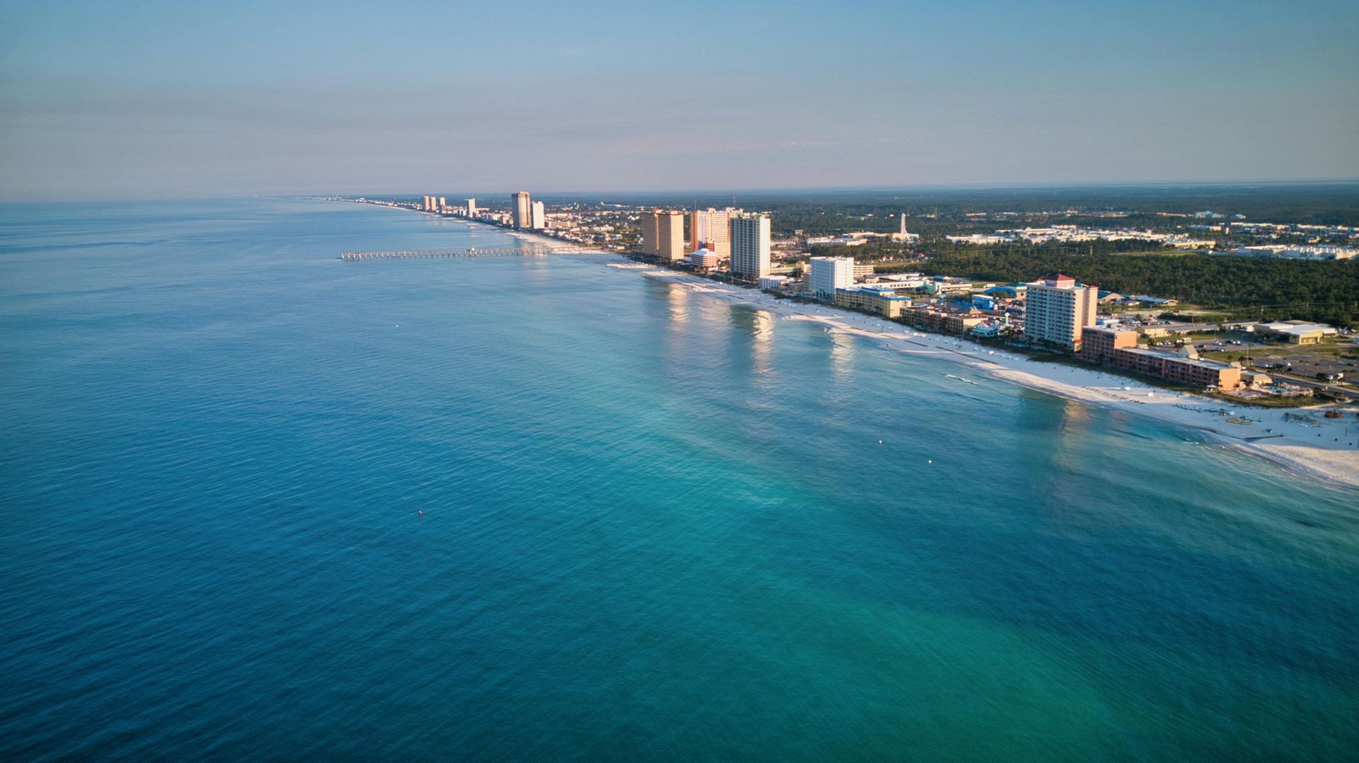 An aerial view of Panama city beach with a city in the background.