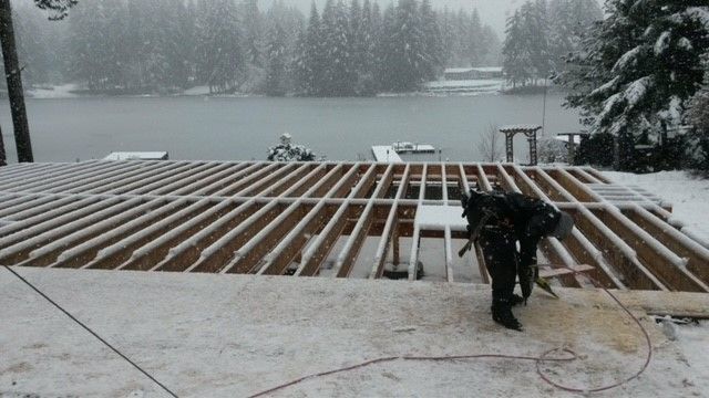 A man is standing on top of a wooden structure in the snow.