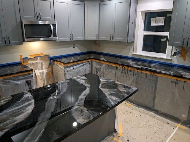 A kitchen with gray cabinets and black counter tops is being remodeled.