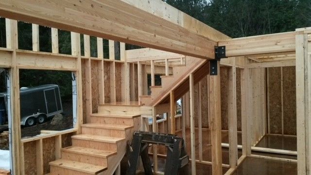 A wooden house is being built with stairs going up to the second floor.