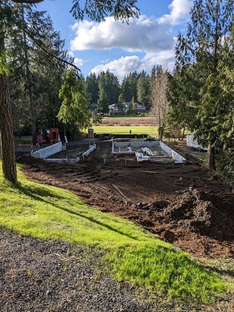 A construction site with a lot of dirt and trees in the background.