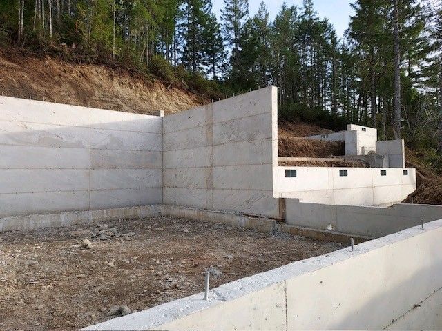 A large concrete wall is being built in the middle of a forest.