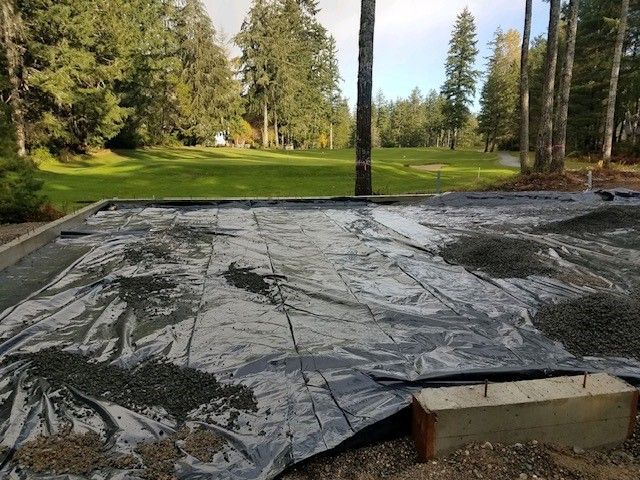 A concrete base is being built in a yard with trees in the background.