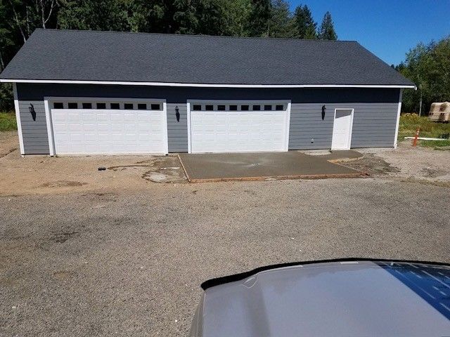 A car is parked in front of a garage with three garage doors